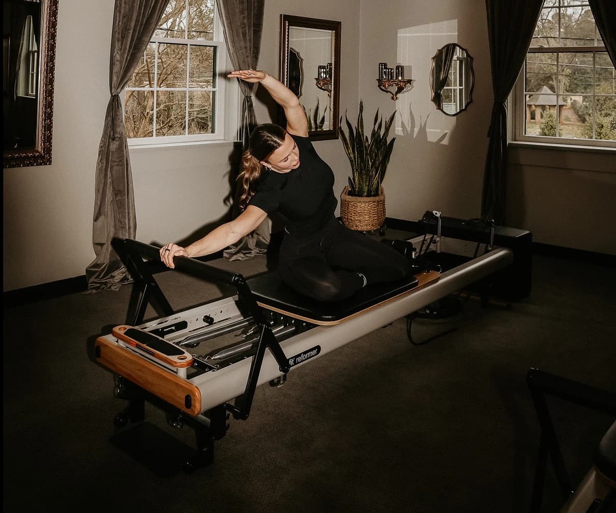 Instructor practicing precise and controlled reformer Pilates movements at Wellness Experience Pilates in Belmont, NC.
